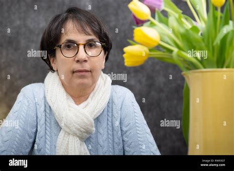 A Portrait Of Attractive Senior Brunette Woman With Glasses Sitting