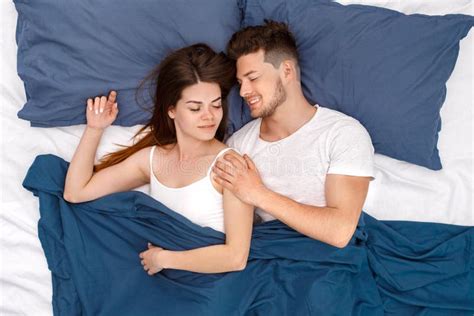 Bedtime Young Couple Lying On Bed Under Blanket Top View Hugging