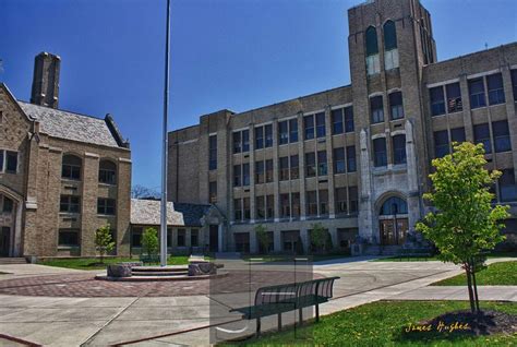 An Old Brick Building With Two Benches In The Foreground And A Flag