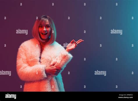 Cheerful Adorable Blonde Woman In Fluffy Fur Coat Sparkly Dress Smile Hold Hand Up Posing