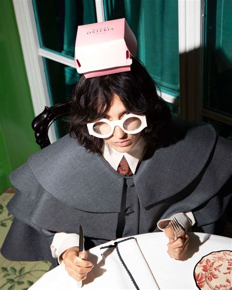 A Woman With Glasses And A Box On Top Of Her Head Sitting At A Table