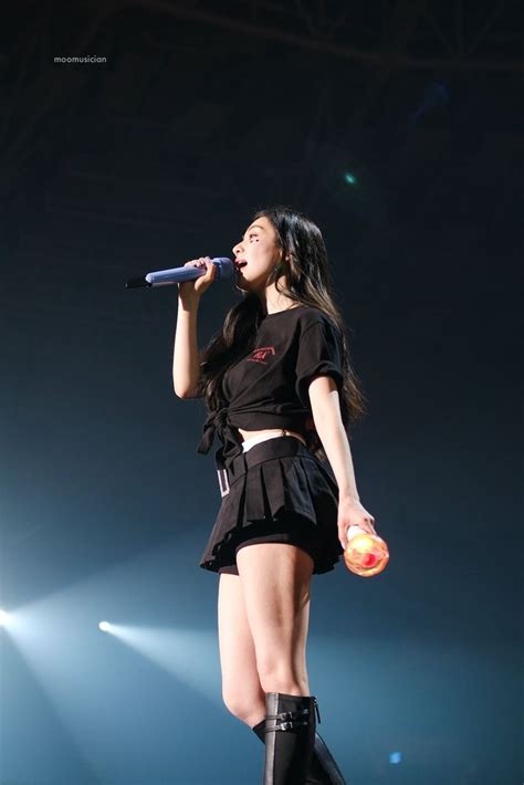 a woman standing on top of a stage with a microphone in her hand and ...