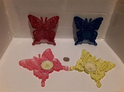 Three Candles Are Sitting In A Box With Butterflies On The Front And Back Of Them