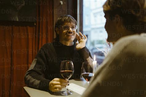 Sonriente Hombre Gay Sosteniendo Copa De Vino Y Hablando Con Su Novio Mientras Est Sentado En