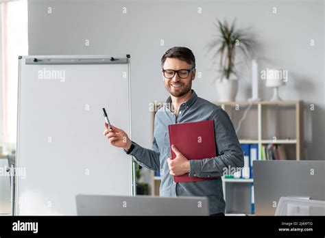 Distance Education Mature Male Tutor Pointing At Empty Blackboard With Mockup Giving Web