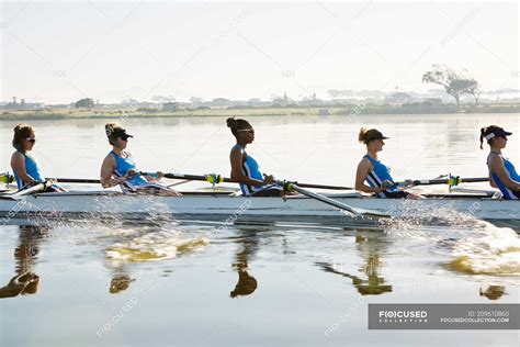 Female rowing team rowing scull on sunny lake — transportation, water ...