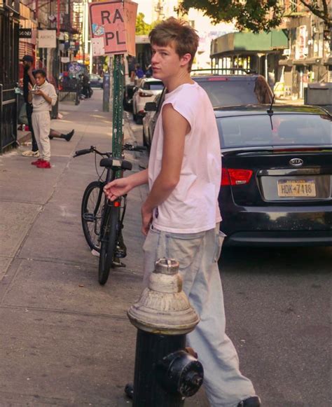 a young man standing next to a fire hydrant on the side of a street