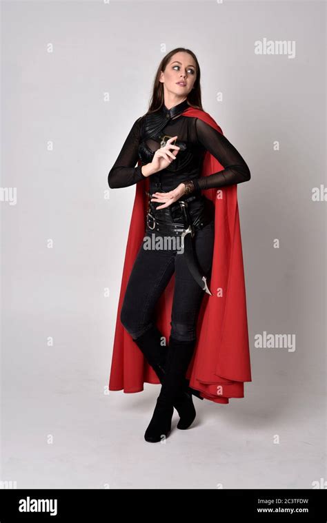 Portrait Of Brunette Girl Wearing Black Leather Catsuit Red Cape Full Length Standing Pose