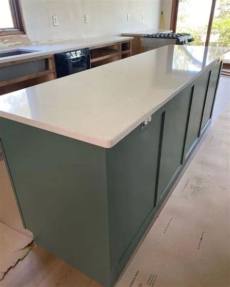 A Kitchen With An Island In The Middle And Cabinets On The Other Side