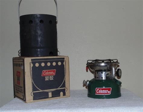 An Old Fashioned Gas Stove Next To A Canister On Top Of A White Table