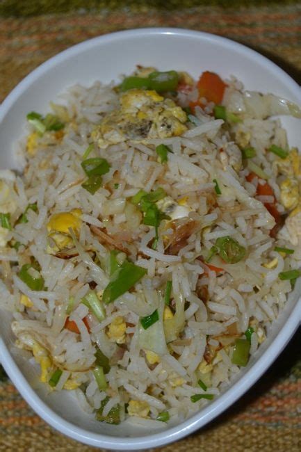 A White Bowl Filled With Rice And Veggies On Top Of A Brown Table