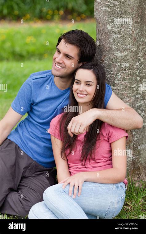 Young Man Placing His Arm Around His Girlfriend While Leaning Against A