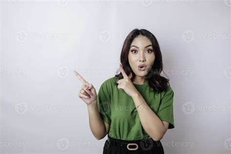 Shocked Asian Woman Wearing Green T Shirt Pointing At The Copy Space Beside Her Isolated By