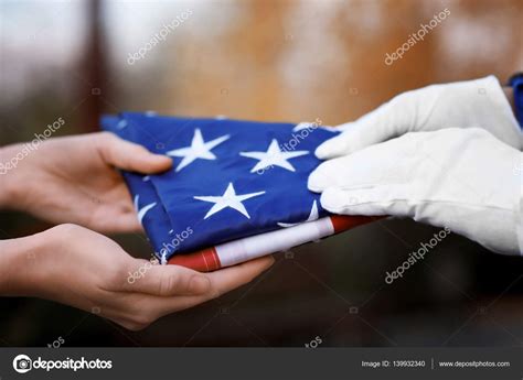 Hands holding folded American flag Stock Photo by ©belchonock 139932340