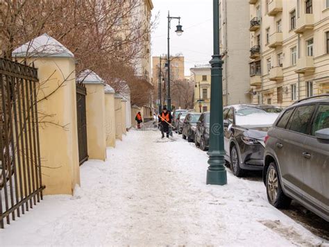 Utility Workers In Orange Vests With Shovels Clean Snow From The