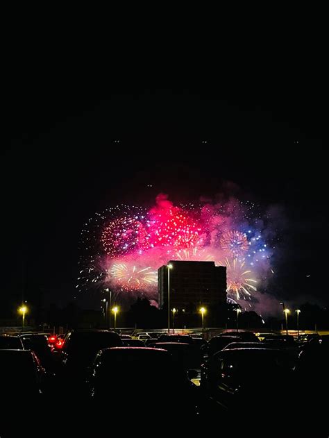 Fireworks Are Lit Up In The Night Sky Over Cars Parked On The Side Of