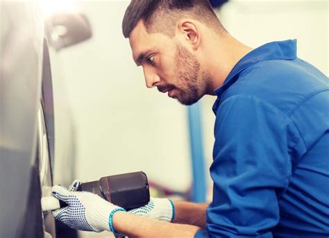 Premium Photo Mechanic With Screwdriver Changing Car Tire