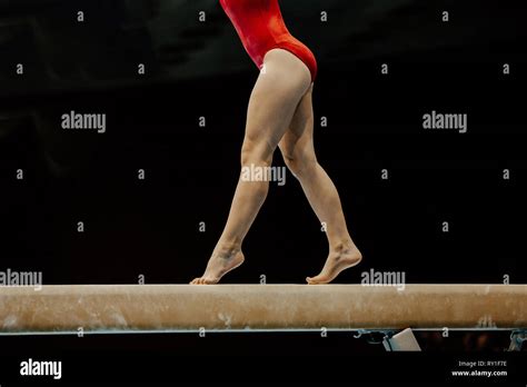 Female Gymnast In Red Leotard On Balance Beam On Black Background Stock