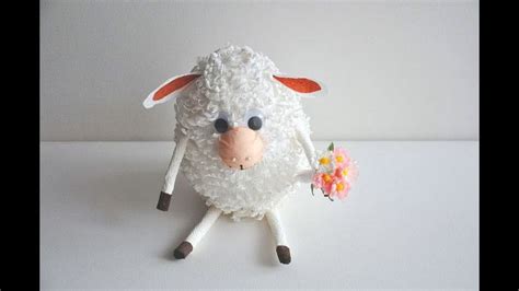 A Stuffed Sheep Holding A Flower On Top Of A White Tablecloth Covered