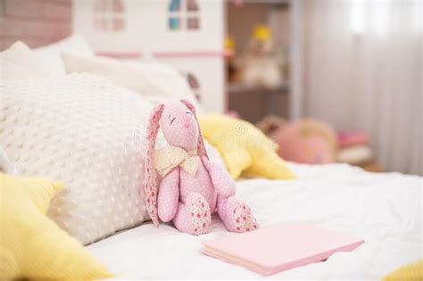 Handmade Plush Rabbit Made Of Fabric Sits On A Cozy Bed In The Children