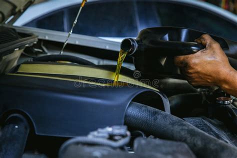 Car Mechanic Replacing And Pouring Fresh Oil Into Engine At Maintenance