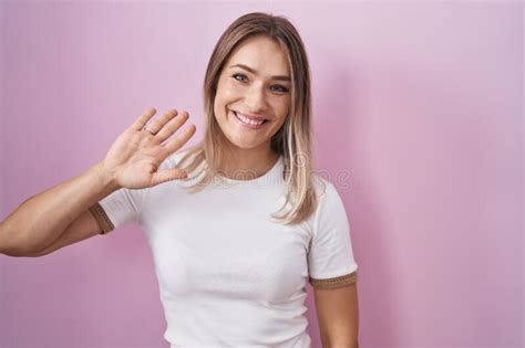 Blonde Caucasian Woman Standing Over Pink Background Waiving Saying