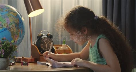 Cute Smart School Age Girl Learning To Write Doing Math Homework Sitting At Home Desk