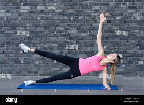 Smiling Beautiful Woman In Pink Top And Black Pants Doing Plank