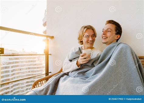 European Gay Couple Hugging While Resting Together On Balcony Stock