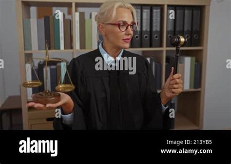Woman Judge In Office Holding Scales And Gavel Blonde With Short Hair Wearing Glasses