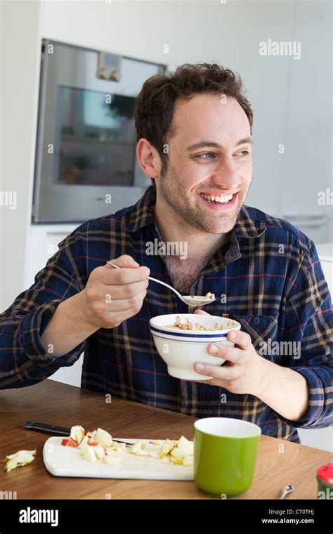 Smiling man eating bowl of cereal Stock Photo - Alamy