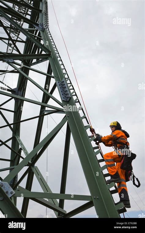 Overhead Transmission Cable Installer Climbing A Mast To Install