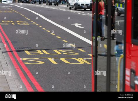 A red London bus traveling in a bus lane and approaching a bus stop in ...