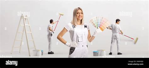 Female House Painter Holding A Color Swatch Palette And Male Workers