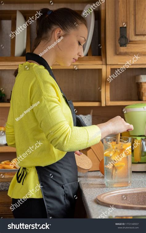 Beautiful Housewife Mixes Freshly Made Fruit Lemonade With Oranges In Real Life Kitchen Interior