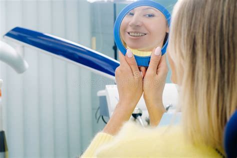 The Girl Smiles And Looks In The Mirror In Dentistry Stock Image