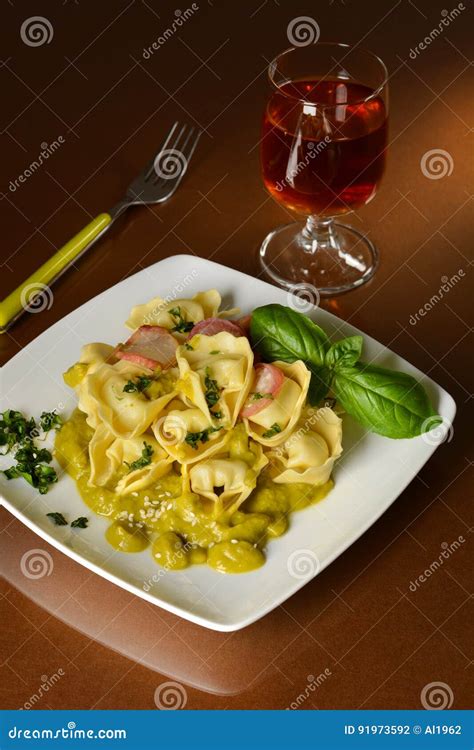 Tortelloni Con Crema De Los Guisantes En El Plato Cuadrado Foto De