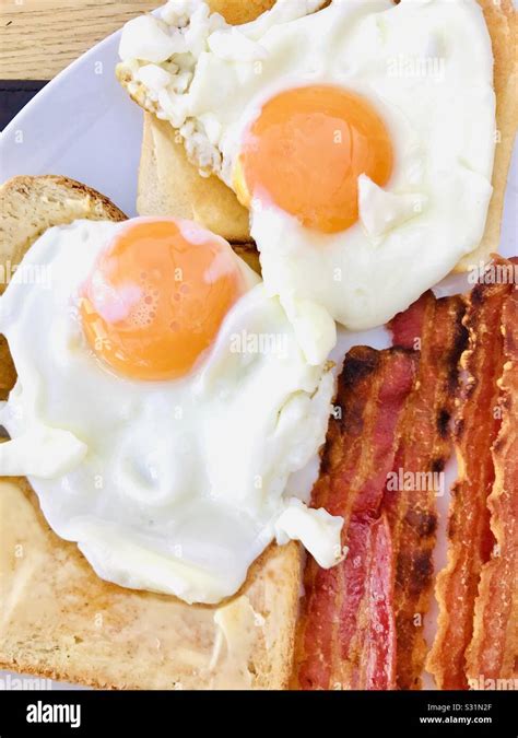 Fried Eggs On White Toast With Crispy Streaky Bacon Stock Photo Alamy