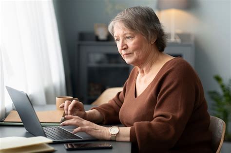 Mulher S Nior Usando Laptop Sentado Na Mesa Na Sala De Estar Foto Gr Tis