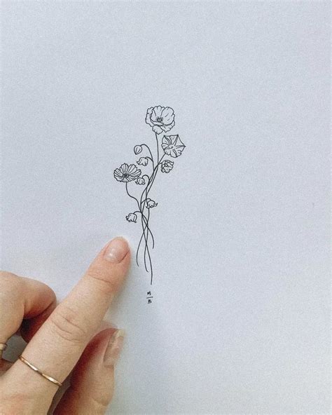 A Hand Is Pointing At A Flower On A Piece Of Paper That Has Been Drawn