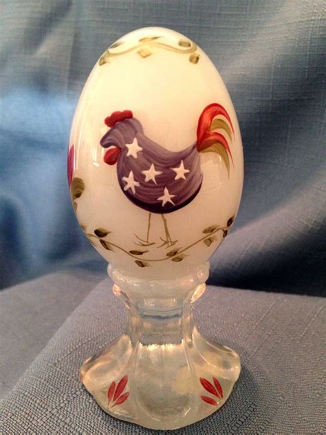 An Egg Sitting On Top Of A Glass Stand With Red White And Blue Designs