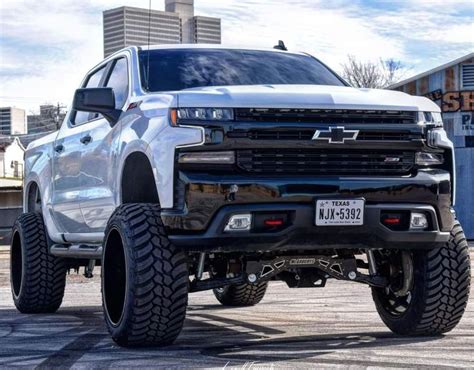 White Lifted Chevy Truck Parked on Top of a Parking Lot