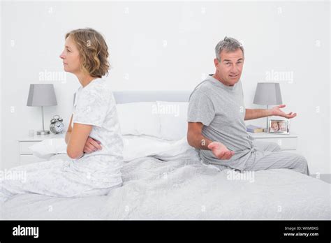 Couple Sitting On Different Sides Of Bed Having A Dispute With Husband