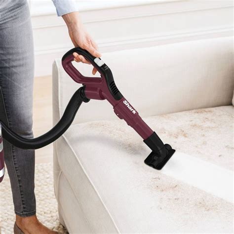 A Person Using A Vacuum To Clean A Couch