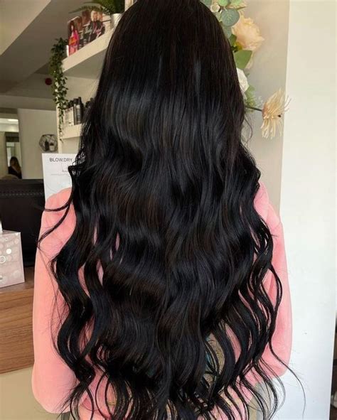 Black hair extensions on a model, showcasing thick, glossy locks. Perfect for autumn, they ...