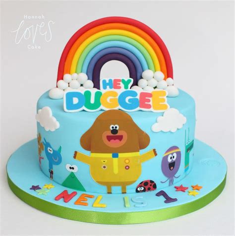 there is a birthday cake that has a dog on it and rainbow in the background