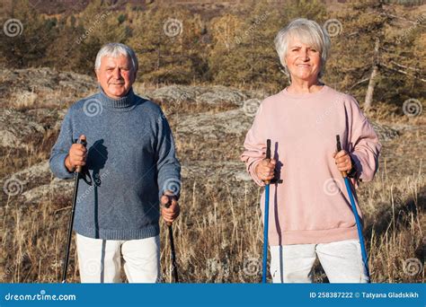 Happy Middle Age Woman And Man Walking With Scandinavian Sticks In