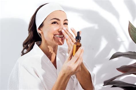 Laughing Woman In A White Bathrobe Takes Care Of Her Skin And