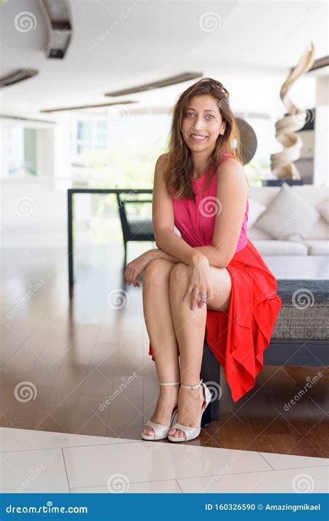 Full Body Shot Of Happy Beautiful Hispanic Woman Sitting At Home