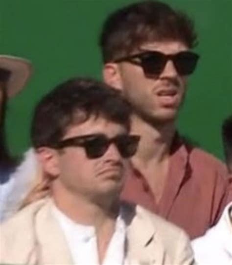 Two Men Wearing Sunglasses And Hats Are Sitting Next To Each Other In